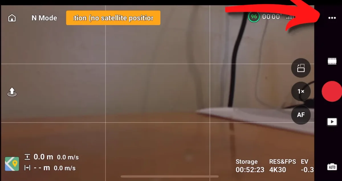 The DJI Fly camera screen with a red arrow pointing to the three-dot system settings button in the top right corner